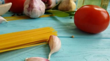 spagetti, bir şişe, sarımsak, domates, karabiber mavi ahşap arka plan, ağır çekim çekim üzerine yağda