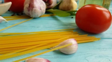 spagetti, bir şişe, sarımsak, domates, karabiber mavi ahşap arka plan, ağır çekim çekim üzerine yağda