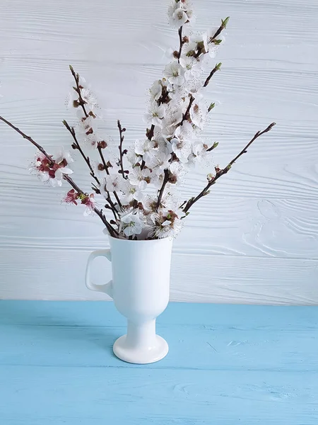 cherry blossom branch in a vase on a colored wooden background, spring,