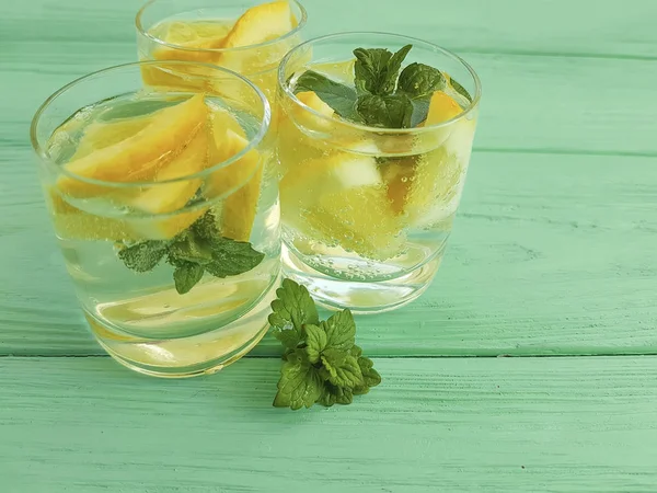 water fresh lemon, mint on a green wooden background