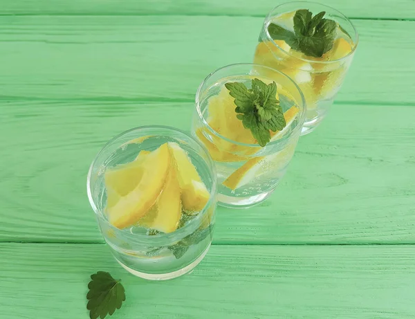 water fresh lemon, mint on a green wooden background