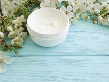 Mavi ahşap arka plan üzerinde kozmetik krem çiçek açması kiraz