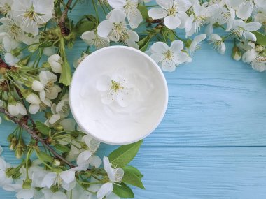 Mavi ahşap arka plan üzerinde kozmetik krem çiçek açması kiraz