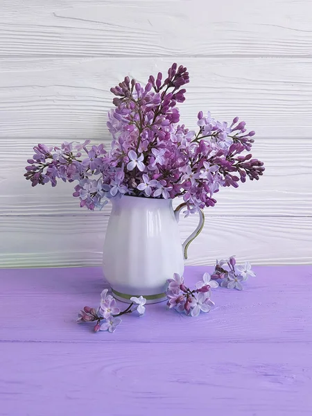 bouquet of lilac in a vase on a wooden background, spring