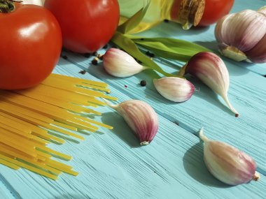 Spagetti kurutulmuş domates sarımsak, biber, mavi ahşap arka planda yağ