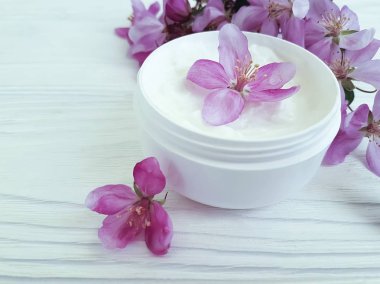 Beyaz tahta üzerinde kozmetik krem pembe çiçekler
