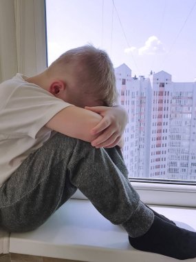 küçük üzgün çocuk üstünde belgili tanımlık pencere oturur 