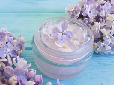 Mavi ahşap arka plan üzerinde güzel leylak çiçeği kozmetik krem