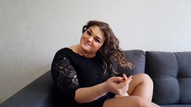 Όμορφη Πλήρης Κορίτσι Που Κάθεται Στον Καναπέ — Αρχείο Βίντεο