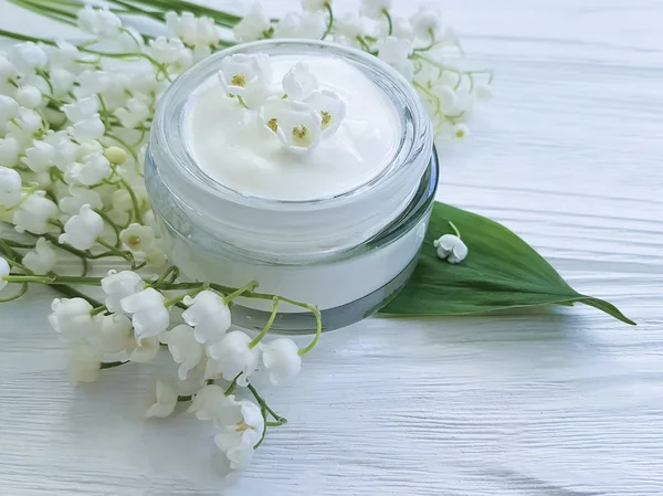 cream cosmetic lily of the valley on a white wooden background