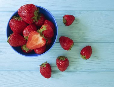 mavi ahşap arka planda taze çilek çanak