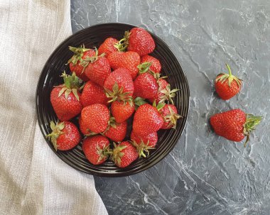 beton bir arka plan üzerinde bir tabak ta taze çilek