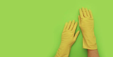 Kadın elleri sarı eldivenli. Renkli bir arka planı temizlemek için.