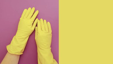 Kadın elleri sarı eldivenli. Renkli bir arka planı temizlemek için.
