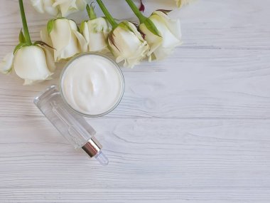 Kozmetik krem, ahşap arka planda gül çiçeği