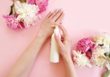 Kadın elleri renkli arka planda kozmetik çiçek şakayığını kremliyor.