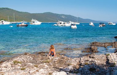 Kayalık sahilde oturan bir genç tabaklanmış kız