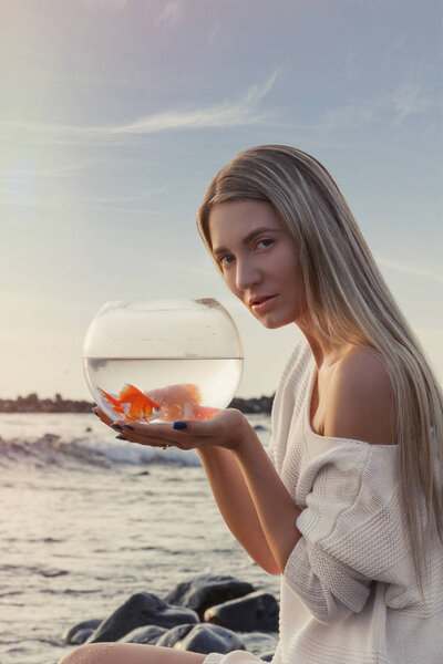 Love nature concept, woman holding golden fish in her hands