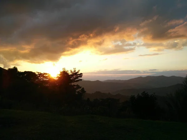 Tarde luz del sol con fantásticas nubes de cielo detrás de la montaña y — Foto de Stock