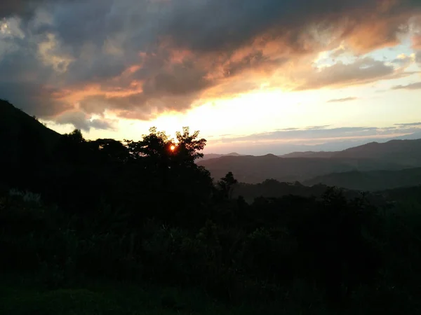 Luz do sol à noite com fantásticas nuvens de céu atrás da montanha e — Fotografia de Stock