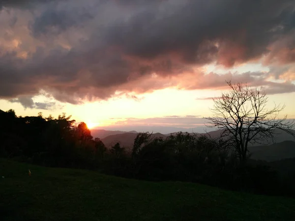 Luz do sol à noite com fantásticas nuvens de céu atrás da montanha e — Fotografia de Stock