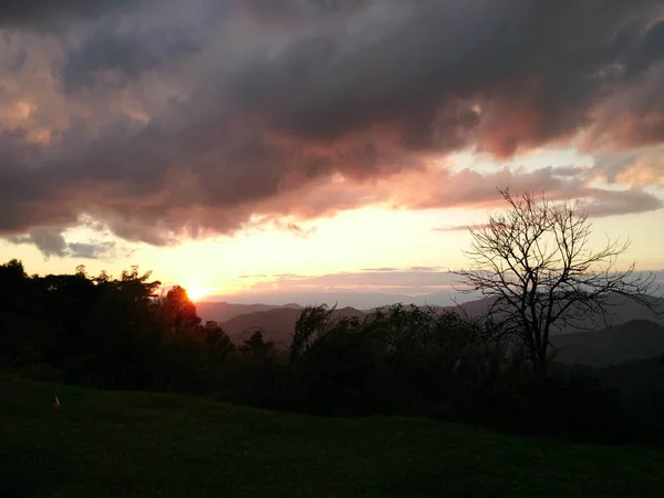 Luz do sol à noite com fantásticas nuvens de céu atrás da montanha e — Fotografia de Stock