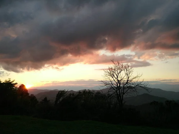 Tarde luz del sol con fantásticas nubes de cielo detrás de la montaña y —  Fotos de Stock