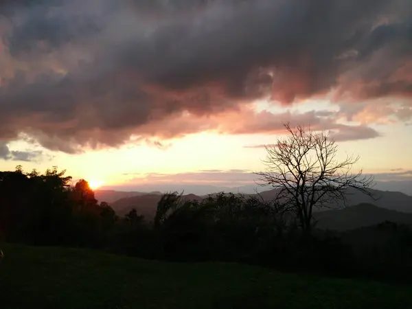 Tarde luz del sol con fantásticas nubes de cielo detrás de la montaña y —  Fotos de Stock