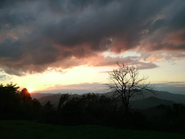Luz do sol à noite com fantásticas nuvens de céu atrás da montanha e — Fotografia de Stock