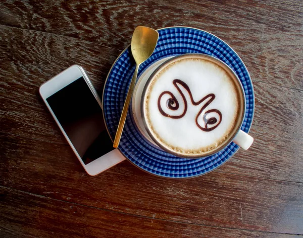 Taza de café y teléfono inteligente en la vieja mesa de madera . — Foto de Stock