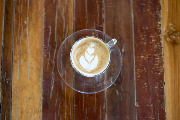 Widok z góry latte art kawy na drewnianym stole. — Zdjęcie stockowe