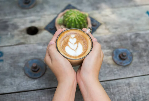 Vrouwelijke handen met een kopje koffie over houten tafel, bovenaanzicht — Stockfoto