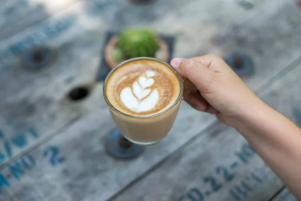 Bir fincan kahve ahşap masa, üstten görünüm üzerinde tutan eller — Stok fotoğraf