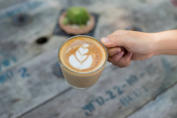 Vrouwelijke handen met een kopje koffie over houten tafel, bovenaanzicht — Stockfoto