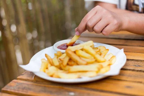 Hand met frietjes duik met tomatensaus. — Stockfoto