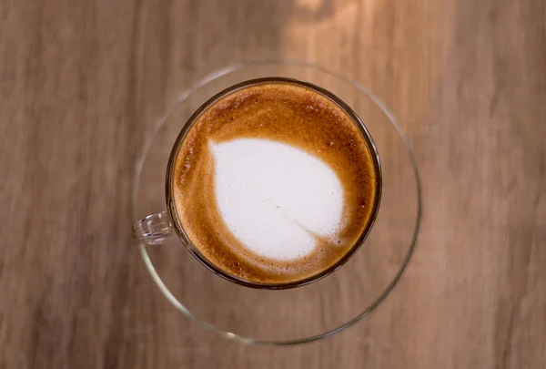Café quente com coração compõem no rosto de creme de leite em copo de vidro — Fotografia de Stock