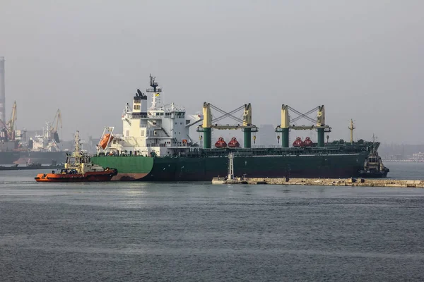 Back view. Tugboat towing a large cargo ship in port. Odessa sea port of Ukraine