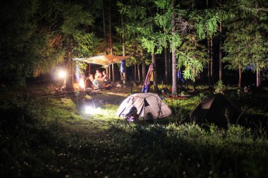 İnsanlar turistik dinlenme gece ormandaki şenlik ateşi yakınlarında kamp var. Altay seferi