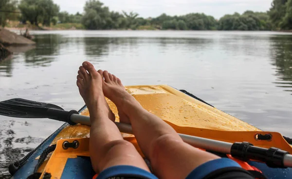 Девушка отдыхает на лодке по реке. Крупный план босых ног. POV — стоковое фото