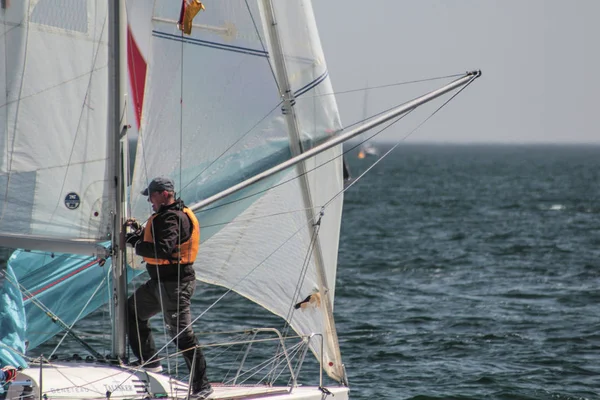 Yachtsman uses mast and forestay to put up spinnaker or mainsail on racing competition yacht or sailboat — Stock Photo, Image