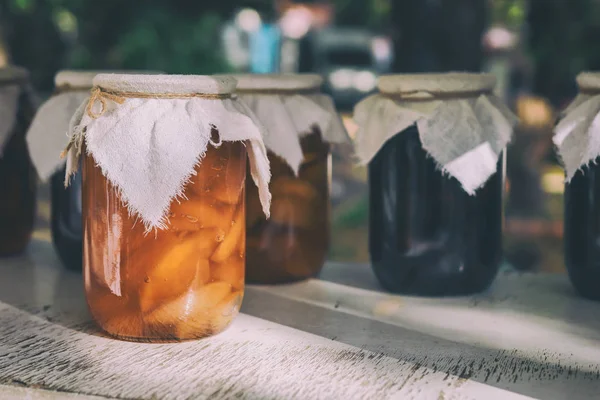 Guci buah buatan sendiri di atas meja kayu. Aprikot kalengan buatan sendiri dalam toples dan aprikot manis di atas meja kayu dengan latar belakang gelap. Aprikot segar yang diawetkan dalam toples sebagai selai buatan sendiri dan jelly . — Stok Foto