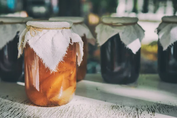 Guci buah buatan sendiri di atas meja kayu. Aprikot kalengan buatan sendiri dalam toples dan aprikot manis di atas meja kayu dengan latar belakang gelap. Aprikot segar yang diawetkan dalam toples sebagai selai buatan sendiri dan jelly . — Stok Foto