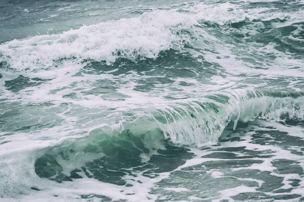 Τα κοντινά κύματα με σπρέι και αφρό στην παραλία είναι ένα αφηρημένο υπόβαθρο. Κοντινό πλάνο, ρηχή εστίαση. — Φωτογραφία Αρχείου