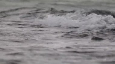 Düşük dalgalı güzel mavi deniz suyu yüzeyi. Deniz manzaralı arka plan. Sakin Kara Deniz Dalgaları. Yakın çekim, sığ odak. Düşük ışık