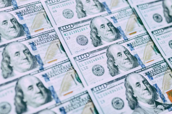 Background of one hundred dollar bills. Benjamin Franklin on USA money banknote.  American dollars banknotes background. US dollars pattern. 100 dollars. Close-up selective focus