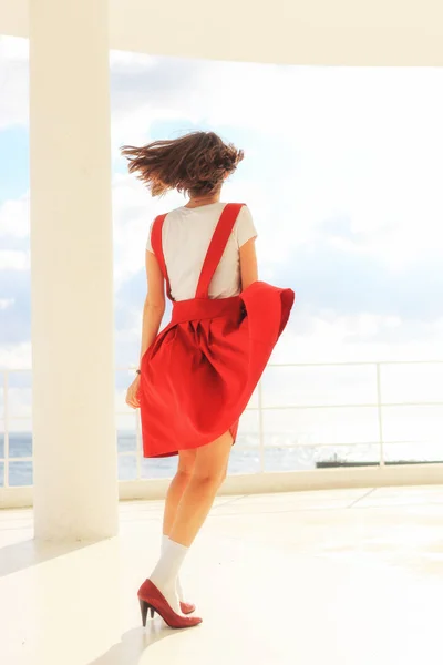 beautiful young woman in sleeveless red sundress on sea background. Fashion woman portrait in red dress outside.