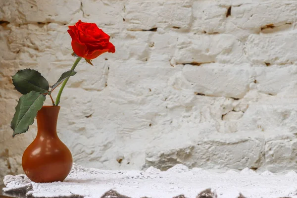 red rose in vase in the table against white  brick wall background