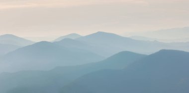 Dağların ve kaya siluetlerinin üstündeki şafak vakti sıcaklığı. Karanlık kayalıkları ve turuncu gündoğumu gökyüzü olan canlı bir dağ manzarası. Minimalist dağ manzarası ile kayalık dağların silueti 