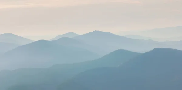 Dağların ve kaya siluetlerinin üstündeki şafak vakti sıcaklığı. Karanlık kayalıkları ve turuncu gündoğumu gökyüzü olan canlı bir dağ manzarası. Minimalist dağ manzarası ile kayalık dağların silueti 