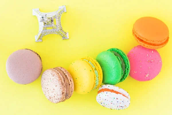 Biscoitos macaroons franceses coloridos doces no fundo amarelo pastel — Fotografia de Stock